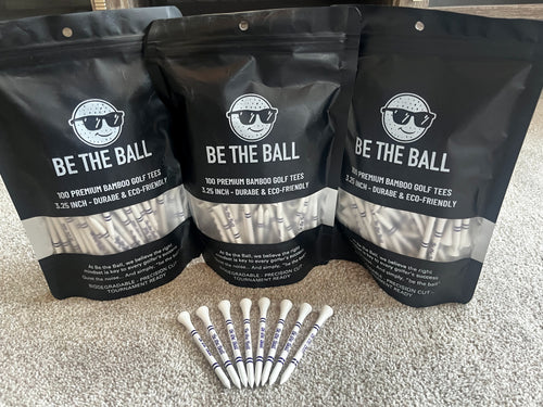 Three packages of 'Be The Ball' golf tees with individual tees displayed on a carpeted floor.
